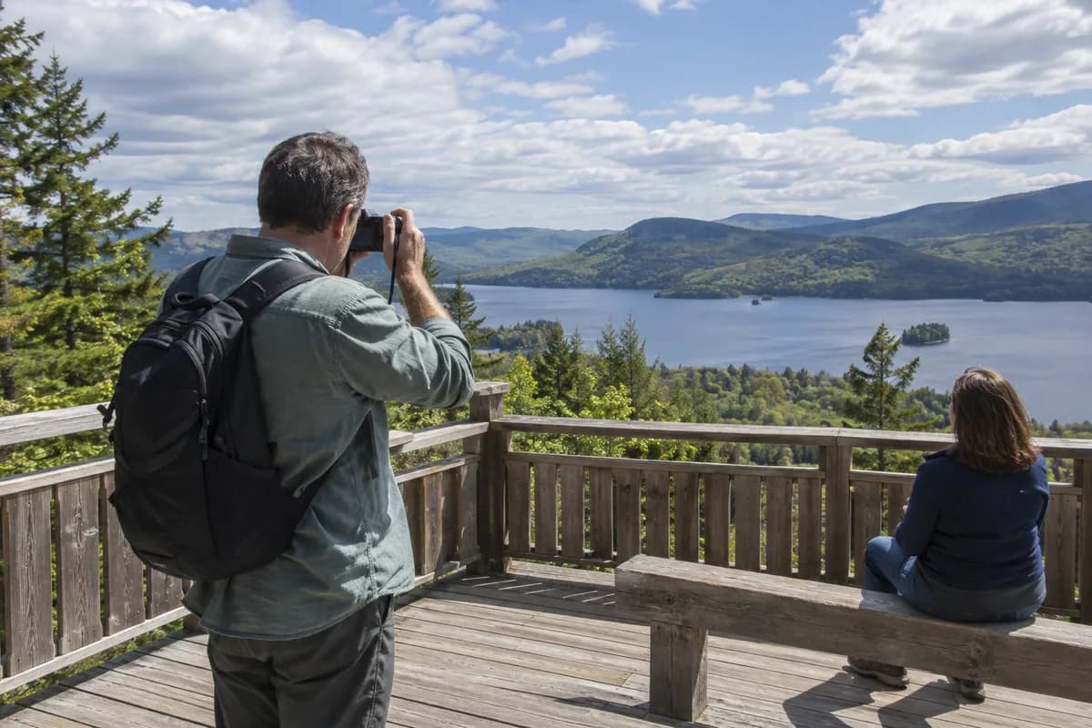 One traveler taking a photograph while a companion sits at a viewpoint.