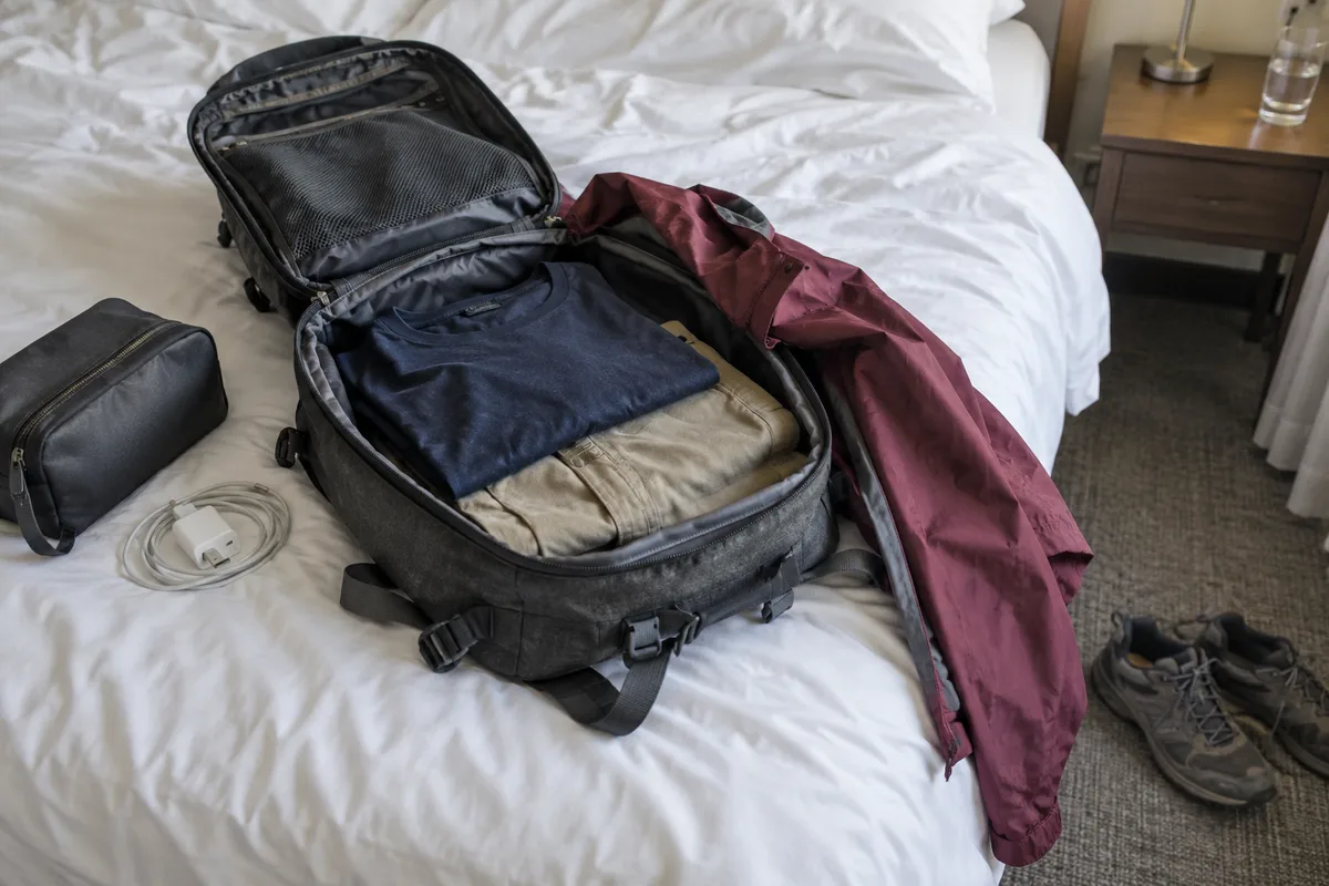 AI-created illustrative scene: An open carry-on bag and everyday walking clothes on a hotel bed.