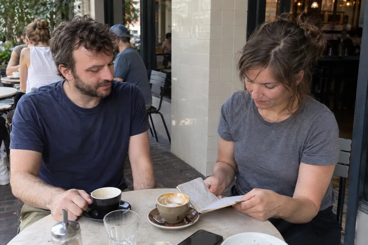 AI-created illustrative scene: Two friends discussing a notebook at a cafe table.